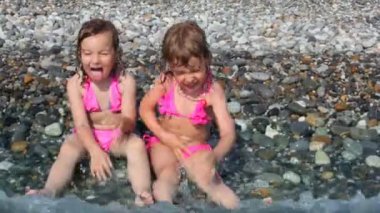 çakıl plajı deniz sörf ile yalan ve su ile oynayan iki küçük kız