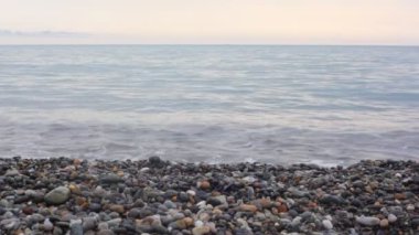 bacakları yalınayak pebble beach, deniz surf arka planda üzerinde yürümeye dostum