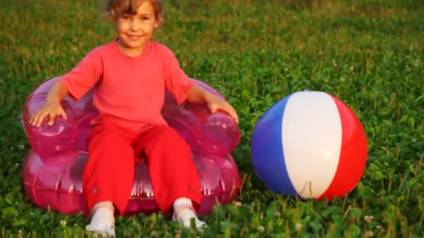 Girl shake in children's inflatable armchair and take ball in hand — Stock Video