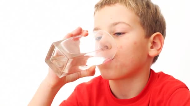 Chico toma el vaso, bebe toda el agua en ella y mira . — Vídeos de Stock