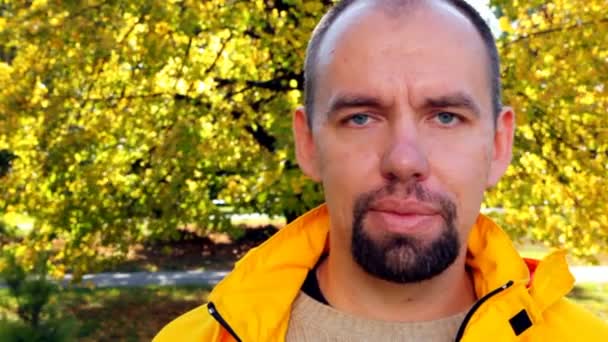 Mans face in yellow jacket close up in park in autumn — Stock Video