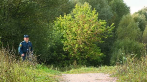 Officier du service de secours marchant sur le sentier dans le parc à la caméra — Video