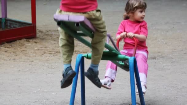 Niño y niña jugar en el balancín juntos en el patio de recreo — Vídeo de stock