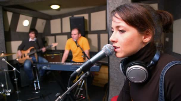 Mujer joven cantando a través de un micrófono en el estudio — Vídeos de Stock