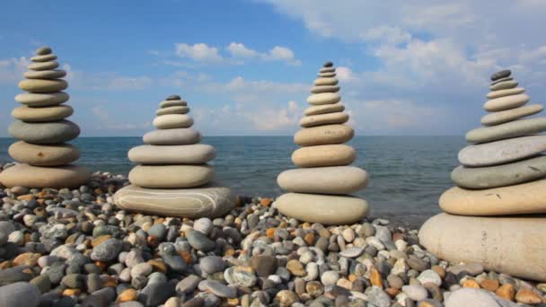Pila de guijarros en la costa de piedra, el mar y el cielo en el fondo — Vídeo de stock