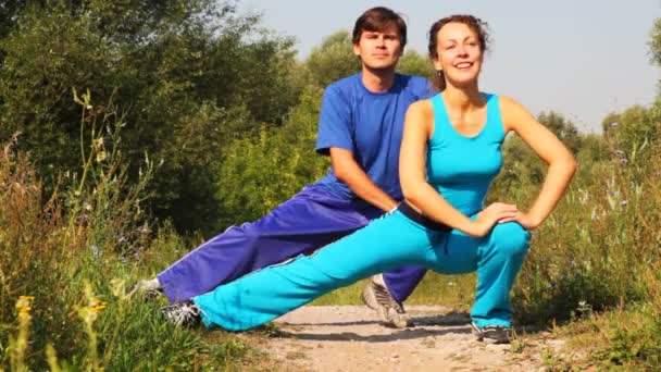 Homme et femme effectuent des exercices sur le chemin dans le parc ensemble — Video