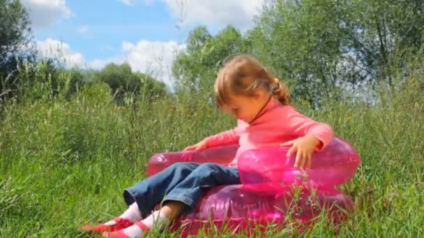 Little cute girl rocking on inflatable chair outdoors in summer park — Stock Video