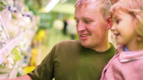 Uomo sorridente con la bambina che compra prezzemolo al supermercato — Video Stock