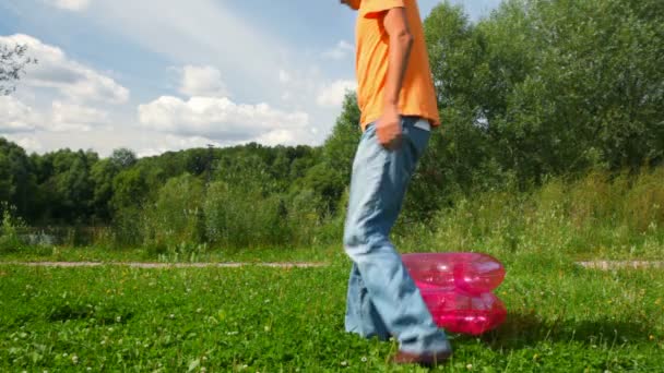 El hombre de anteojos va y se sienta en la silla inflable al aire libre — Vídeos de Stock