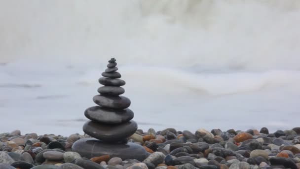 Pila de piedra en la costa de guijarros, agitando el mar en el fondo — Vídeos de Stock