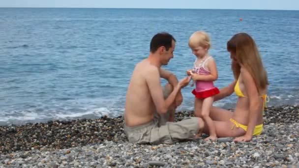 Familia feliz en la playa de guijarros, niña dando cuentas a su padre — Vídeo de stock