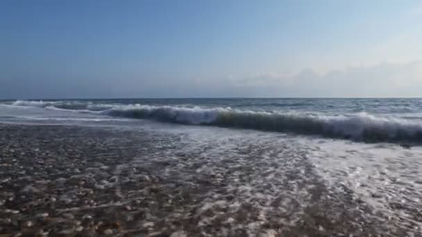 Dalgalanan deniz ve gökyüzü bulutlu, çakıl plajı üzerinde sörf — Stok video