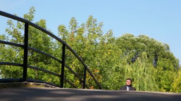 Man dressed in suit walking on bridge, to camera — Stock Video