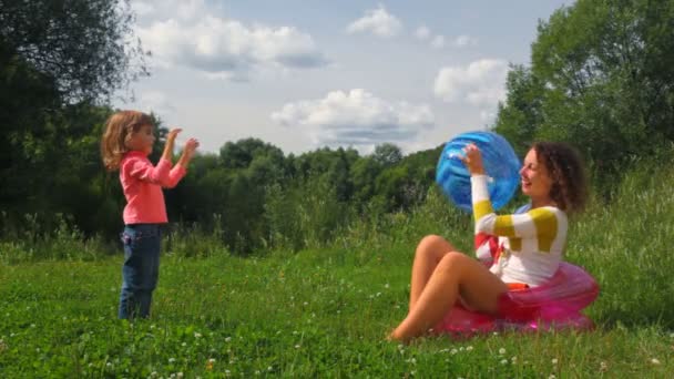 Niña y mujer joven jugando con pelota inflable al aire libre — Vídeos de Stock