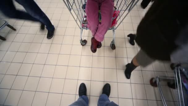 Comprador con cámara y carrito de compras va en el centro comercial, vista en el piso — Vídeos de Stock