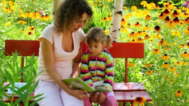 Mamma läser med dotter på bänken på gården — Stockvideo