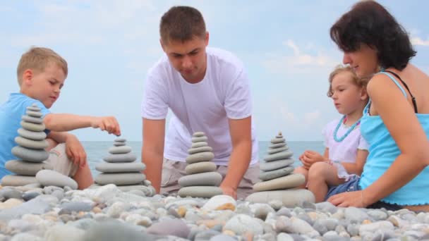 家族の建物の小石のビーチ、バック グラウンドで海に石のスタック — ストック動画