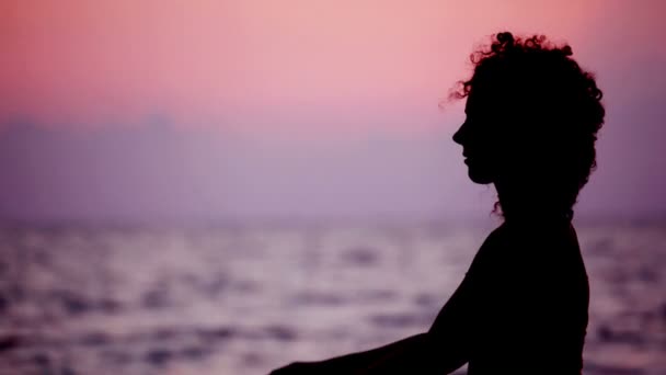 Silhouette of woman with sea star in hands on beach, sunset sea in background — Stock Video