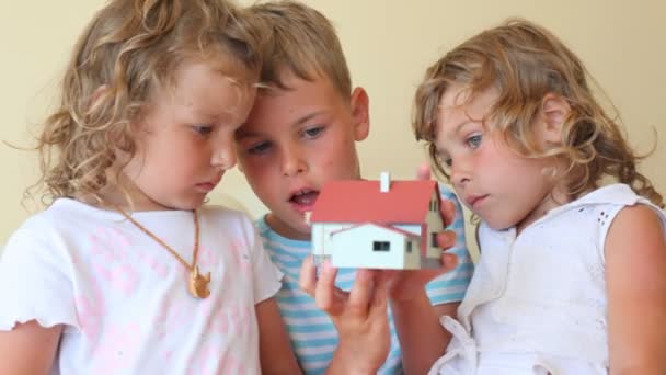 Две маленькие девочки и мальчик с игрушечным домиком внутри — стоковое видео