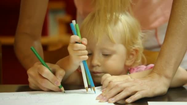 Oidentifierad kvinna med liten flicka ritning pennor på vitt papper — Stockvideo