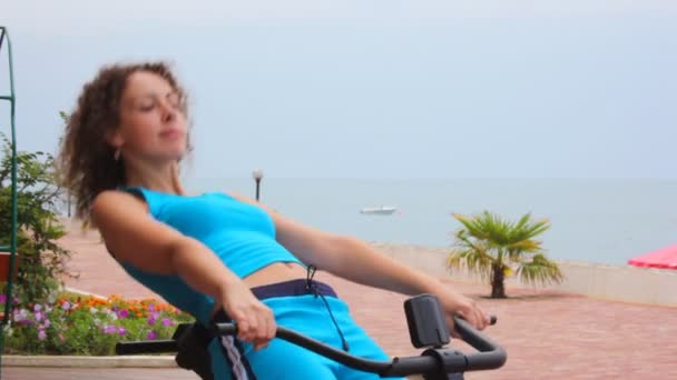 Feliz entrenamiento de mujer joven en aparatos de gimnasio, mar en el fondo — Vídeos de Stock