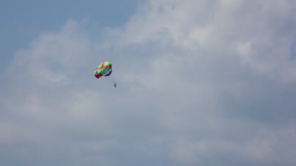 Parasailing, homem com paraquedas de cor voando no céu com nuvens — Vídeo de Stock
