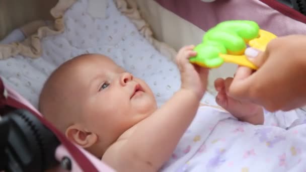 Bebé tratando de sentarse mientras sostiene las manos de las madres — Vídeo de stock