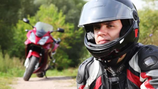 Motorradfahrer sitzt neben Motorrad, sieht und wendet — Stockvideo