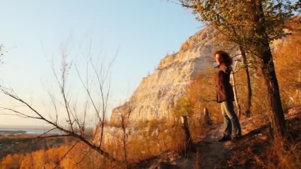 Женщина стоит, протянув руки на тропинку против горы и леса осенью — стоковое видео