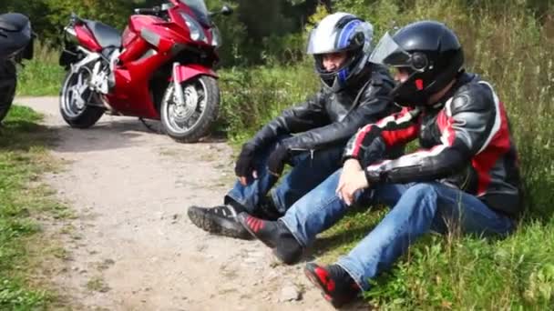 Dos motociclistas se sientan cerca de sus motocicletas en el parque, cámara móvil — Vídeos de Stock