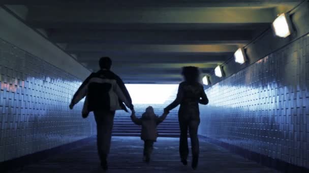 Família de três pessoas que correm em passagem subterrânea da câmera, mãos unidas — Vídeo de Stock