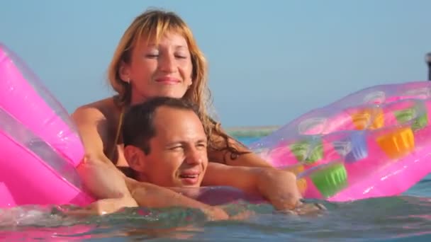 Woman and man embracing on inflatable mattress in swimming pool — Stock Video