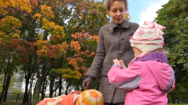 Jonge moeder praten met haar dochter en zoon permanent in park — Stockvideo