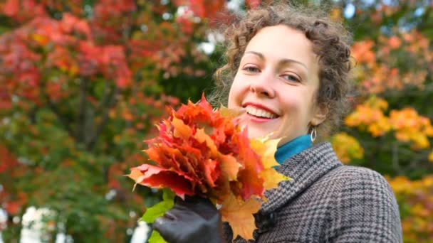 Retrato de una joven sonriente con hojas de otoño en el parque — Vídeos de Stock