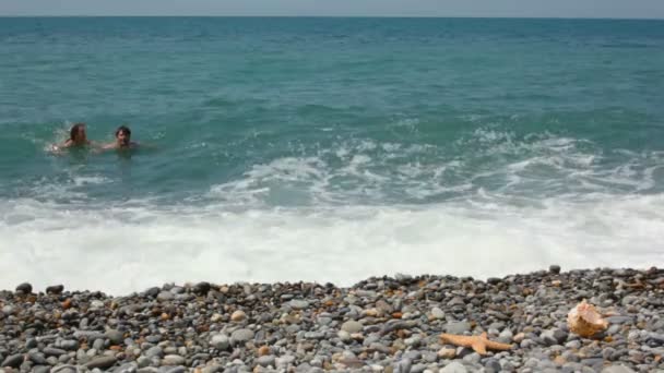 Человек плавает в море, затем вышел из воды и подходит к камере — стоковое видео