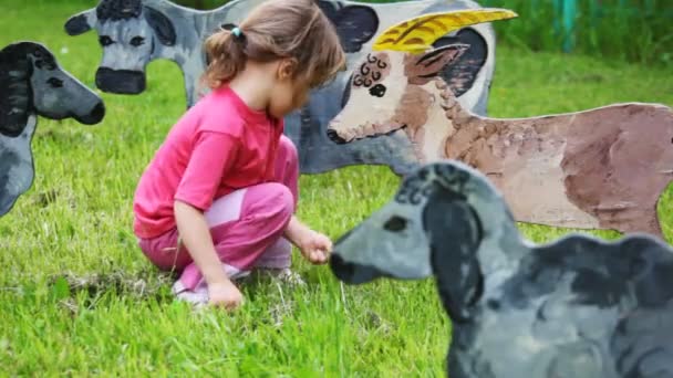 Girl on lawn feeds with grass drawn silhouette of nanny-goat — Stock Video