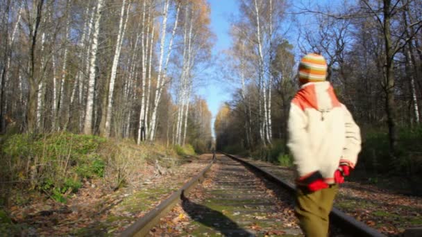 Jongen wandelen langs railroad tracks, van camera — Stockvideo