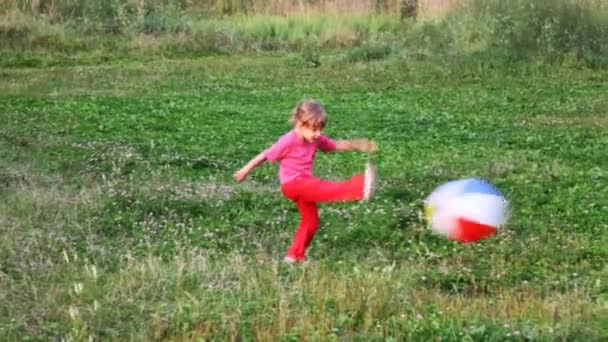 Liten flicka går bakom bollen över fältet i park — Stockvideo
