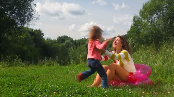 La bambina corre dalla madre seduta sul sedile gonfiabile e abbraccia — Video Stock