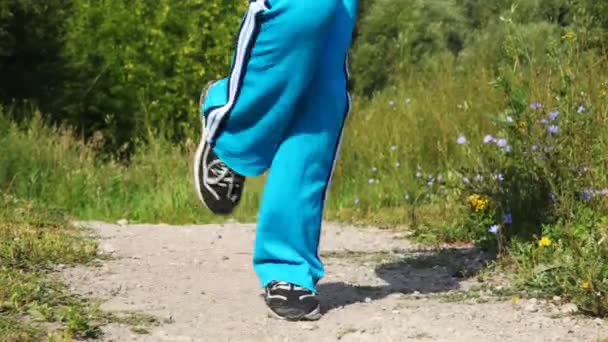 Gros plan des pieds de la fille qui effectuent des exercices sur la route dans le parc — Video