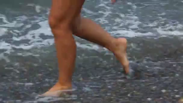 Pieds avec pédicure de femme marchant sur la plage rocheuse avec surf de mer — Video