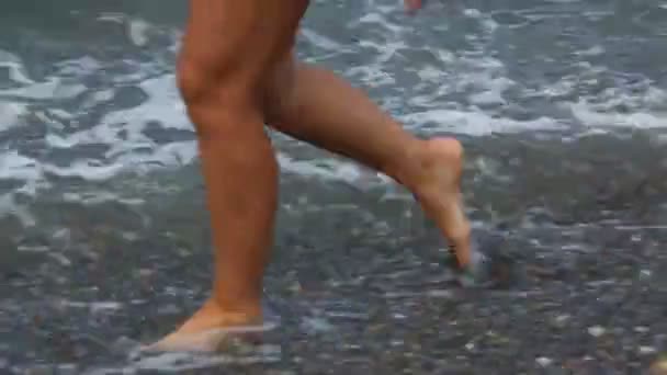 Feet with pedicure of woman walking on rocky beach with sea surf — Stock Video