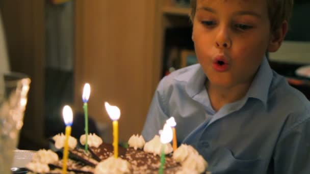 Chico soplando velas en la torta — Vídeo de stock