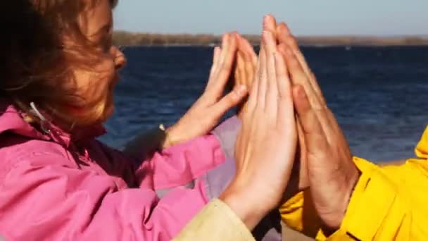 Filha e pai brincam um com o outro em palmas na costa do rio — Vídeo de Stock