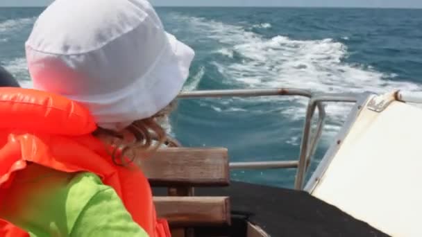 Retrato de menina no colete salva-vidas sentado em ir cortador olha para o mar — Vídeo de Stock