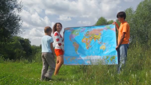 Hombre y mujer sosteniendo mapa político en el parque de verano, niño buscando país — Vídeos de Stock