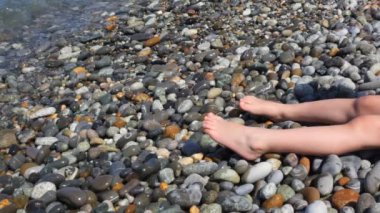 küçük kızın çakıl plajı deniz sörf yanında otururken ayaklar