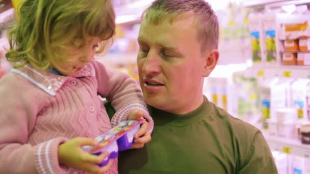Мужчина с маленькой девочкой покупает йогурт в супермаркете — стоковое видео