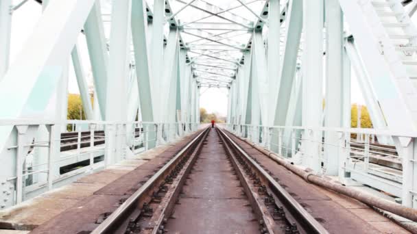 Roodharige jongeman gaat vooruit op camera op spoorbrug — Stockvideo