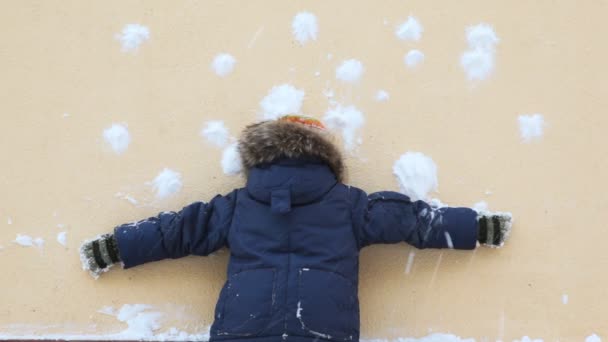 男孩站在墙上和在它射雪球 — 图库视频影像